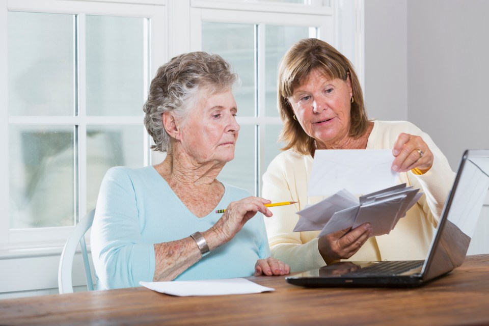 A mature woman (60s) helping her elderly mother (90s) pay bills.