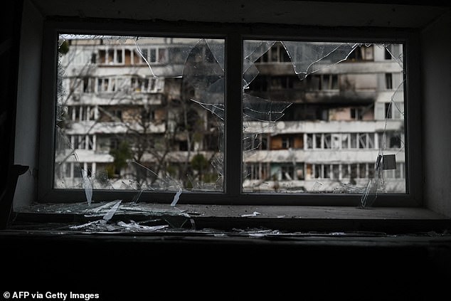 A broken window and a damaged residential building in the background following an air attack in Kyiv, November 25, 2025