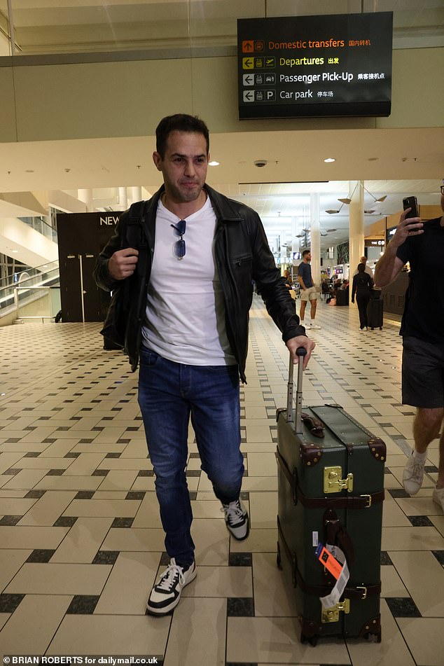 Jeremy sported a casual figure as he walked through the arrivals hall, donning a muscle white t-shirt with jeans and a black leather jacket