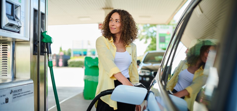 Woman filling car with petrol at a gas station.