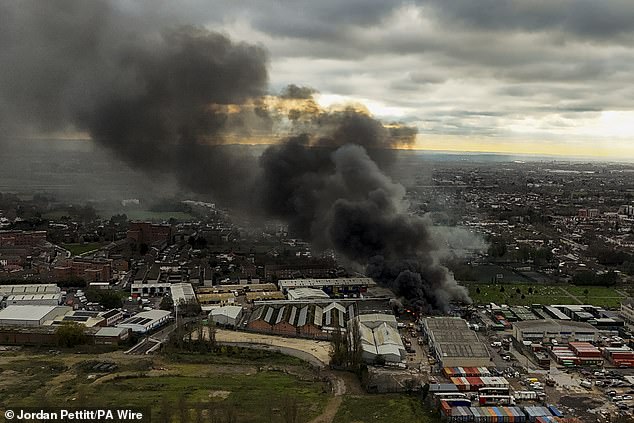 A giant plume of smoke towers into the air as the blaze tears through the warehouse
