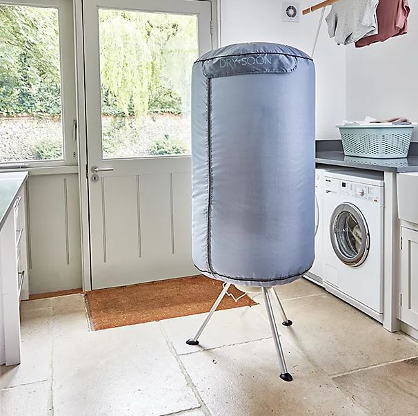 A 'Dry Soon' clothes dryer with a light blue fabric covering in a laundry room.