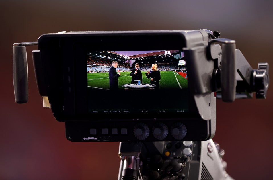A TV camera monitor showing three broadcasters on a soccer field at Villa Park.