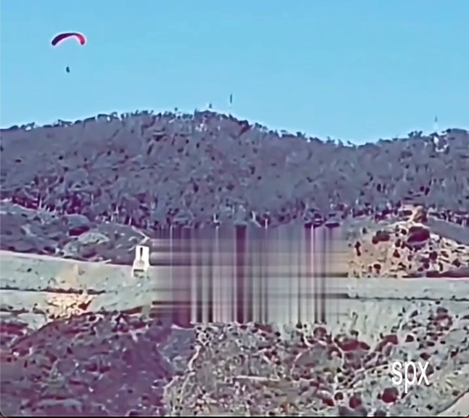 A paraglider flying over a border fence into Ceuta.