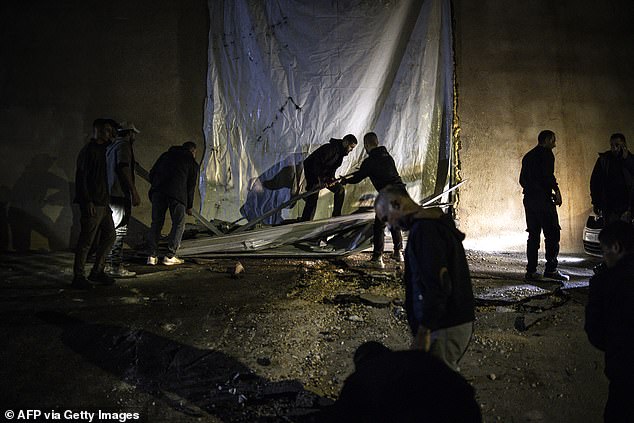 People help clean the site of a reported shooting that left two Palestinians dead during a military operation in the occupied West Bank city of Jenin on November 27, 2025
