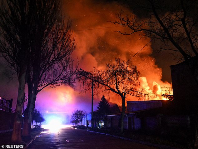 A resident stands on a street while buildings burn after an evening Russian drone strike, amid Russia's attack on Ukraine, in Zaporizhzhia, Ukraine November 25, 2025