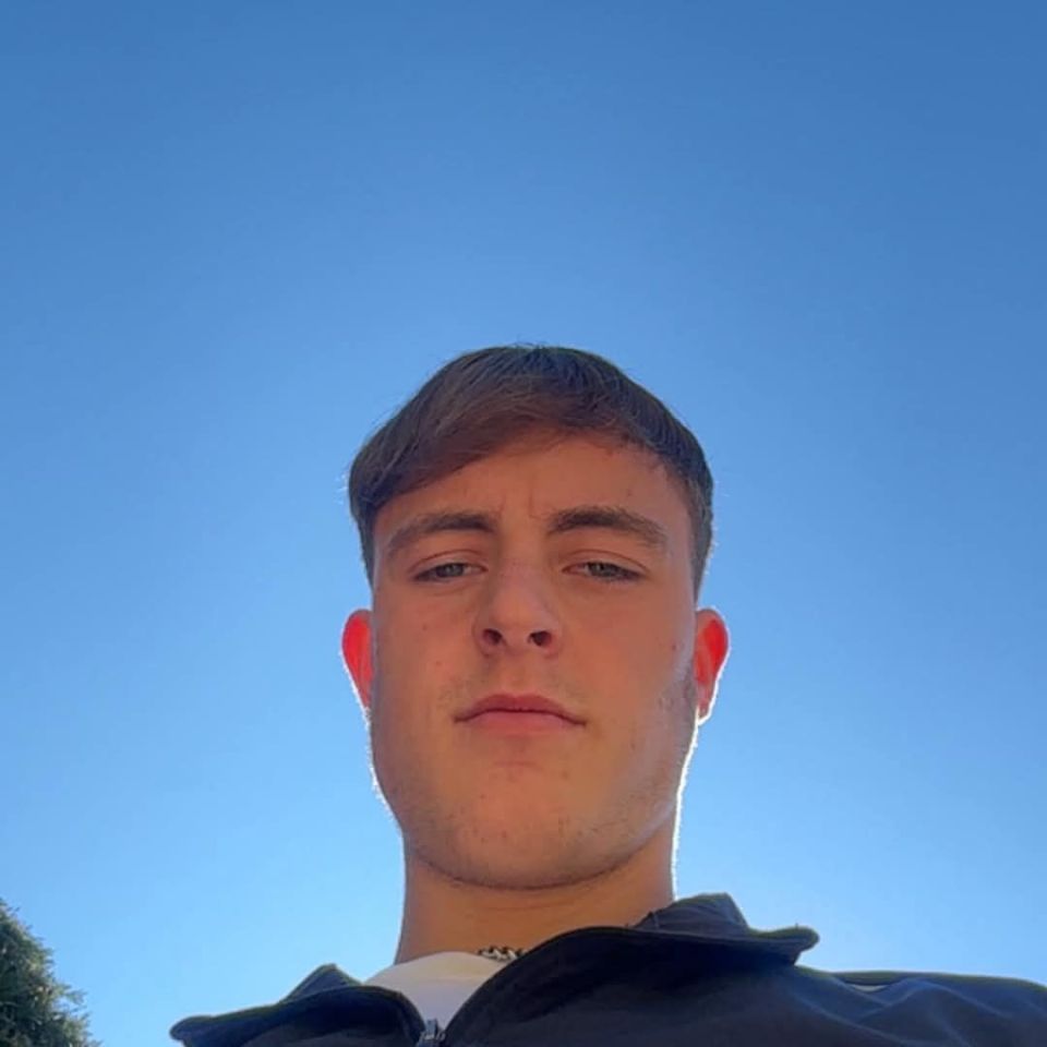 Ethan Powell, a young man with brown hair, looks directly at the camera with a blue sky behind him.