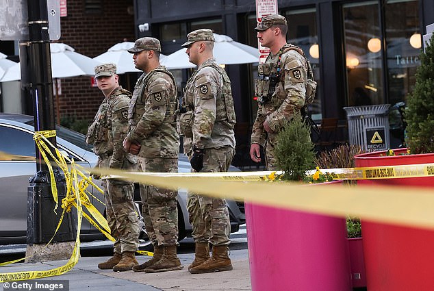 Pictured: Soldiers gather in a cordoned off area where the West Virginia National Guard members were shot on Wednesday