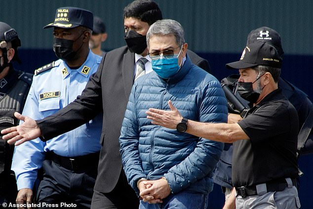 Former Honduran President Juan Orlando Hernandez, second from right, is taken in handcuffs to a waiting aircraft as he is extradited to the United States, at an Air Force base in Honduras, in April 2022