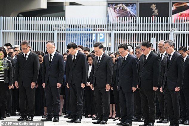 Hong Kong's Chief Executive John Lee (C) and other government officials observe three minutes of silence to mourn victims of the Wang Fuk Court residential estate fire