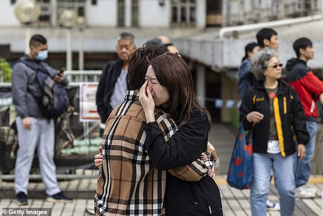 A woman is seen crying near residential buildings that continue to burn at Wang Fuk Court in the Tai Po district on November 27, 2025 in Hong Kong, China