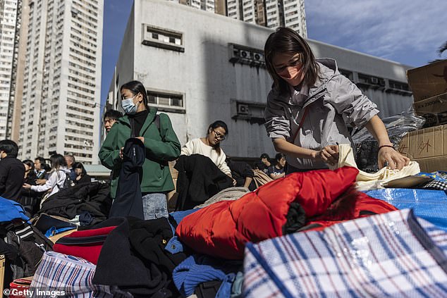 People look at donated clothes near residential buildings damaged by fire at Wang Fuk Court in the Tai Po district on November 28, 2025 in Hong Kong, China