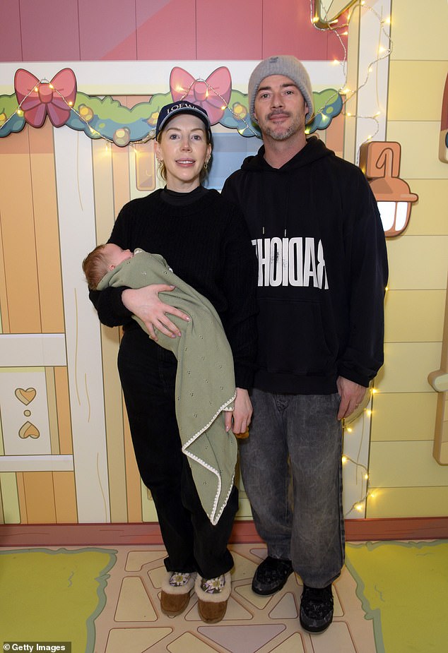 She completed the look with UGG ballet flats and a navy Loewe baseball cap, as she held onto the tot, who was wrapped up warm in a green blanket