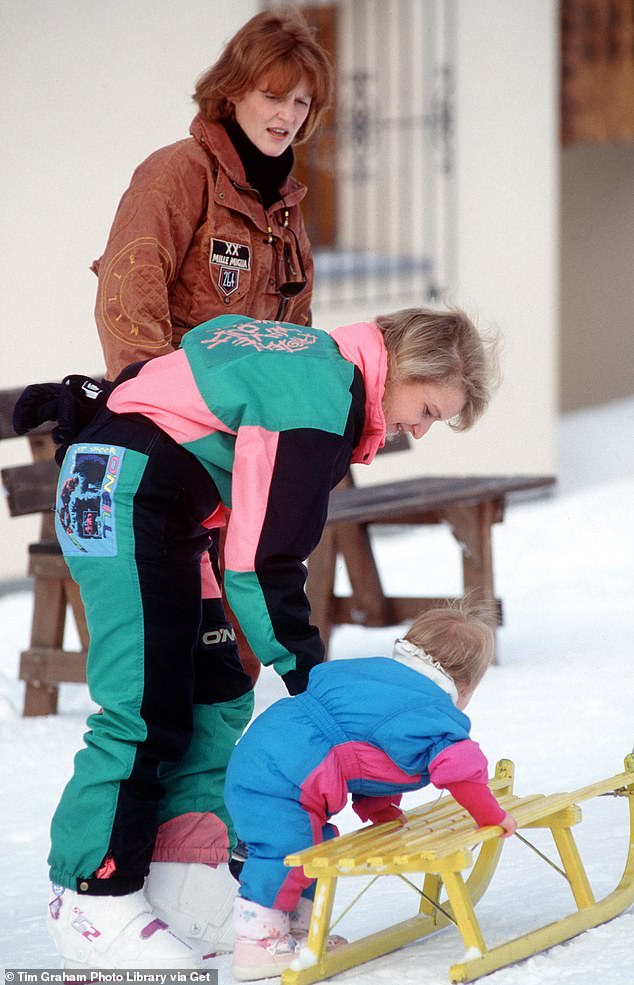 Nanny Alison Wardley helping Princess Eugenie onto A sledge while on holiday In Klosters with Fergie watching