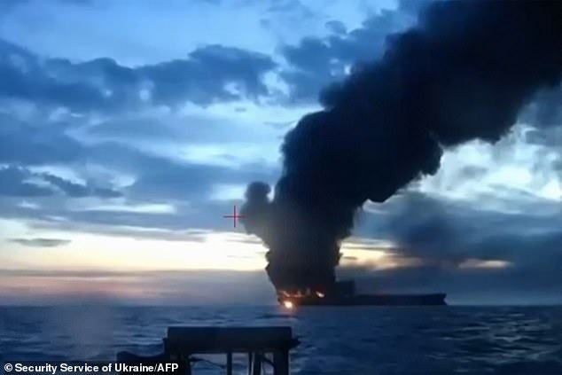 Sparks scatter into the air as the blast tears through the vessel, leaving a sheet of fire across the water and a trail of smoke stretching for miles