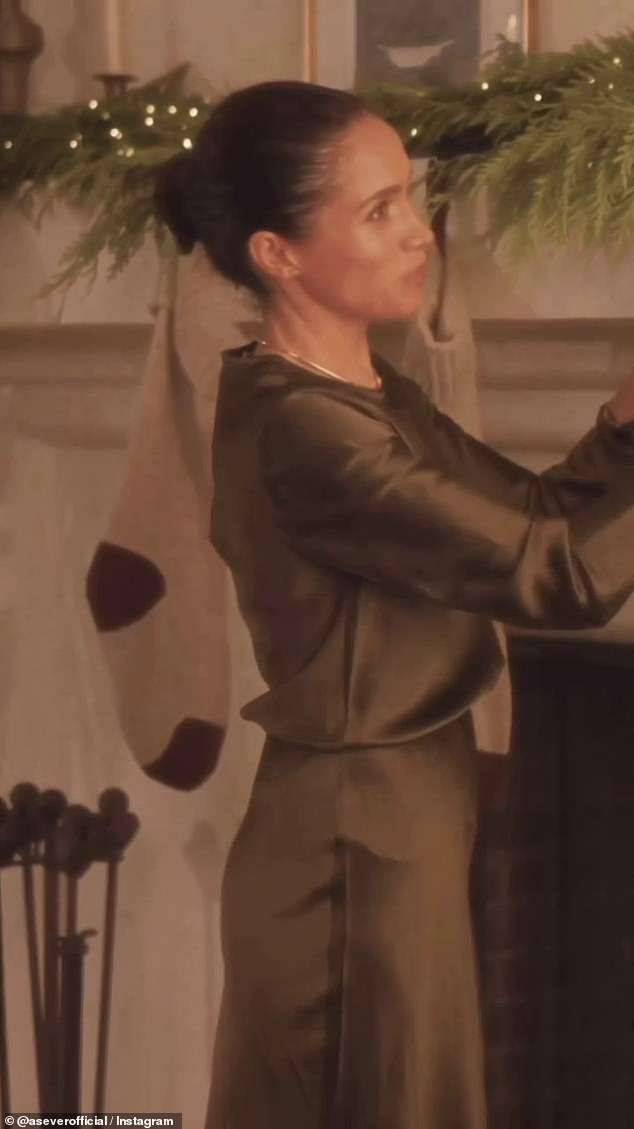 Hanging stockings on the fireplace, Meghan is stylishly dressed in a matching olive green £200 silk top and £190 skirt from New York based brand Argent