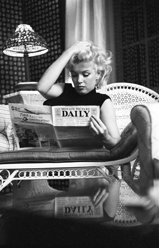 Marilyn Monroe kicks her feet up as she reads the Motion Picture Daily newspaper