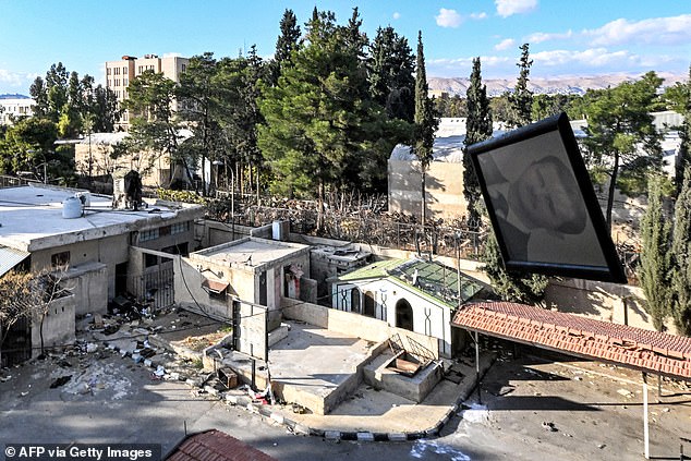 A picture of Syria's ousted president Bashar al-Assad is tossed out of a window from the prison facility run by the 'Palestine Security branch' of Syria's Military Intelligence Directorate in Damascus on December 13, 2024