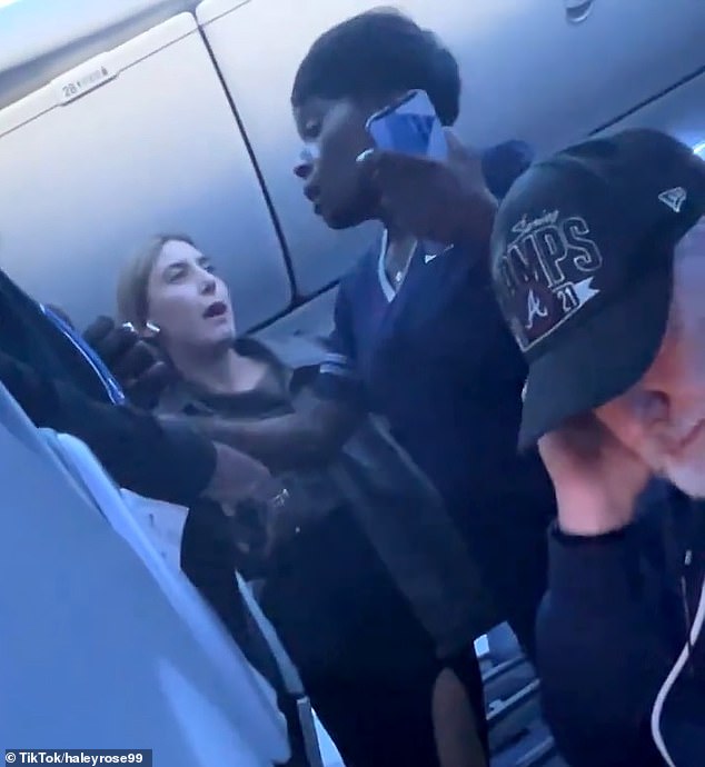 The unnamed woman is seen getting close to a female flight attendants face as she cursed and screamed after waiting on the tarmac for over an hour