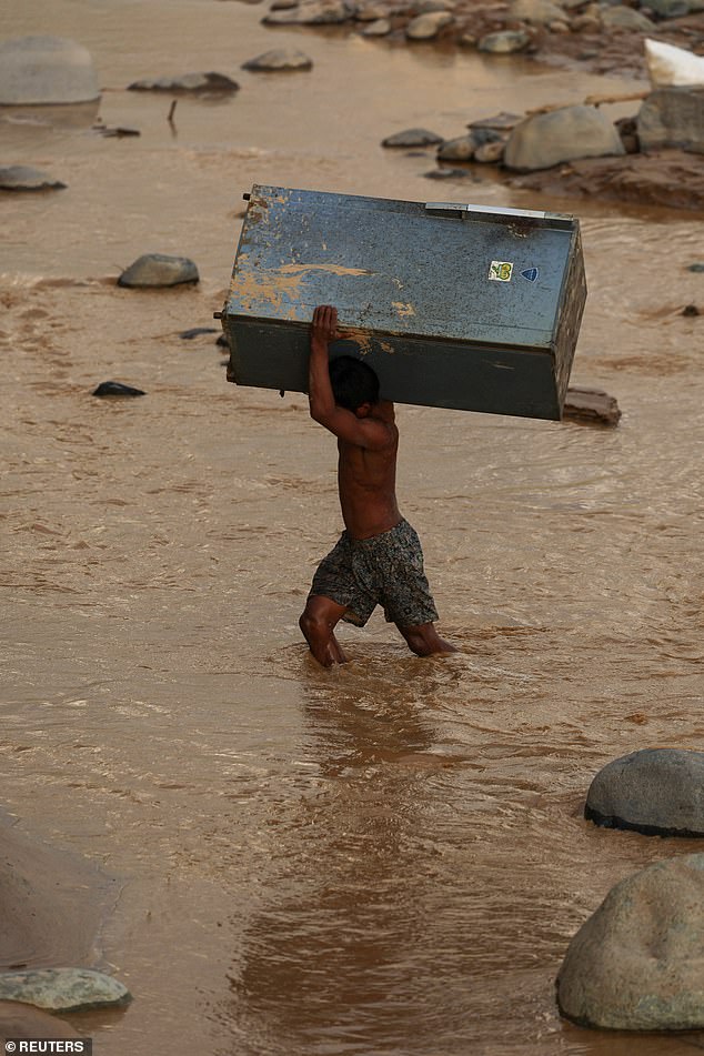 A man carries a refrigerator on his shoulders as he attempts to leave for a safer area following heavy rains in Padang, West Sumatra