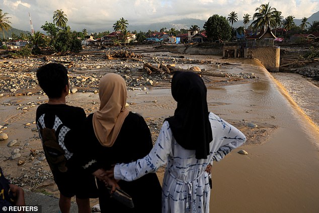 Local residents comfort one another as they look at the devastation caused by flooding
