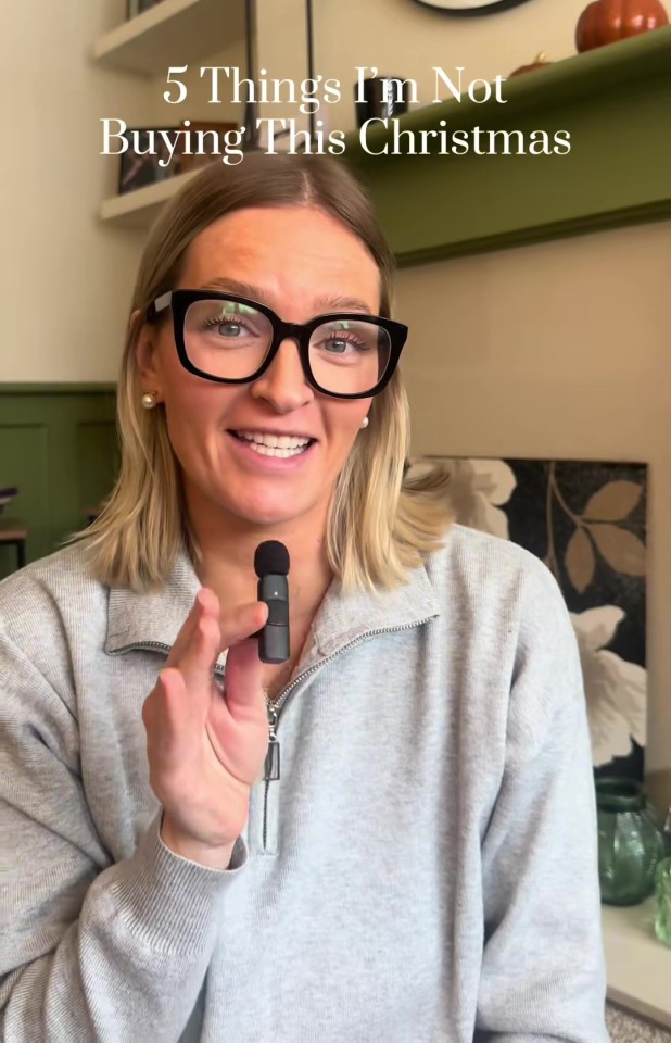 A woman with black glasses holds a microphone and smiles, with text "5 Things I'm Not Buying This Christmas" superimposed over the image.