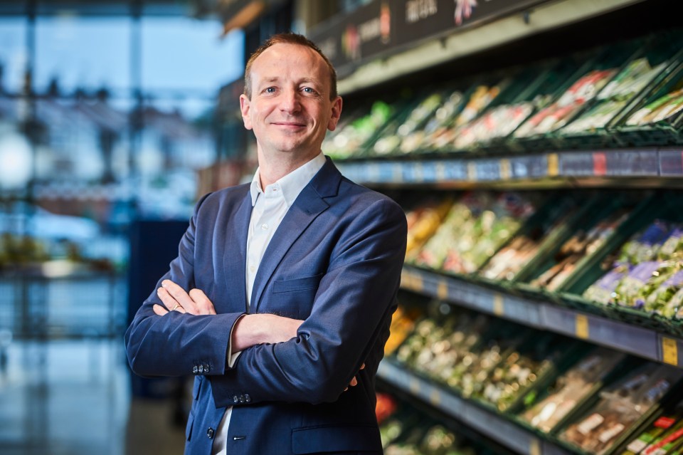 Giles Hurley, Aldi CEO, standing in an Aldi store with his arms crossed.