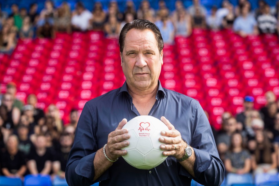 David Seaman holding a British Heart Foundation football in front of empty seats at Selhurst Park.