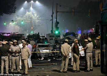 Security personnel stand beside charred vehicles at the blast site after an explosion near the Red Fort in the old quarters of Delhi on November 10, 2025