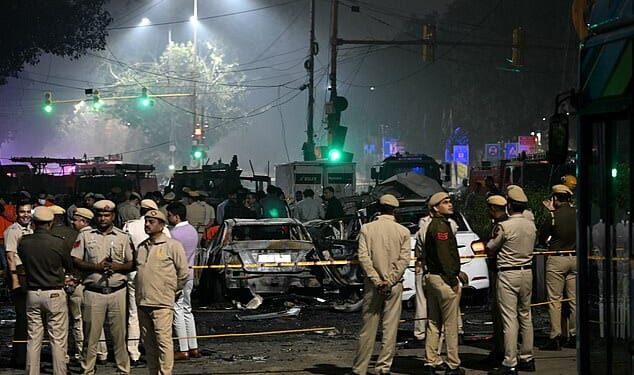Security personnel stand beside charred vehicles at the blast site after an explosion near the Red Fort in the old quarters of Delhi on November 10, 2025