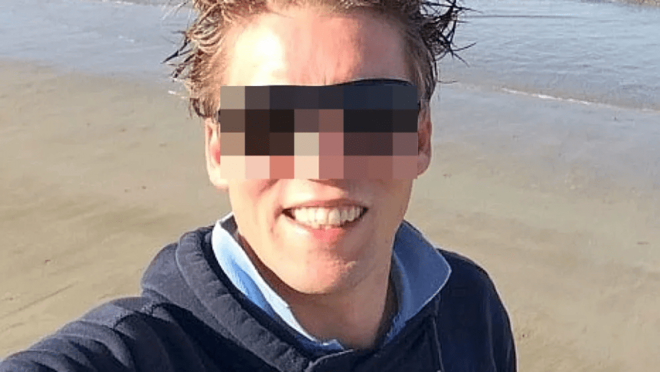 A man with pixelated eyes smiling on a beach.