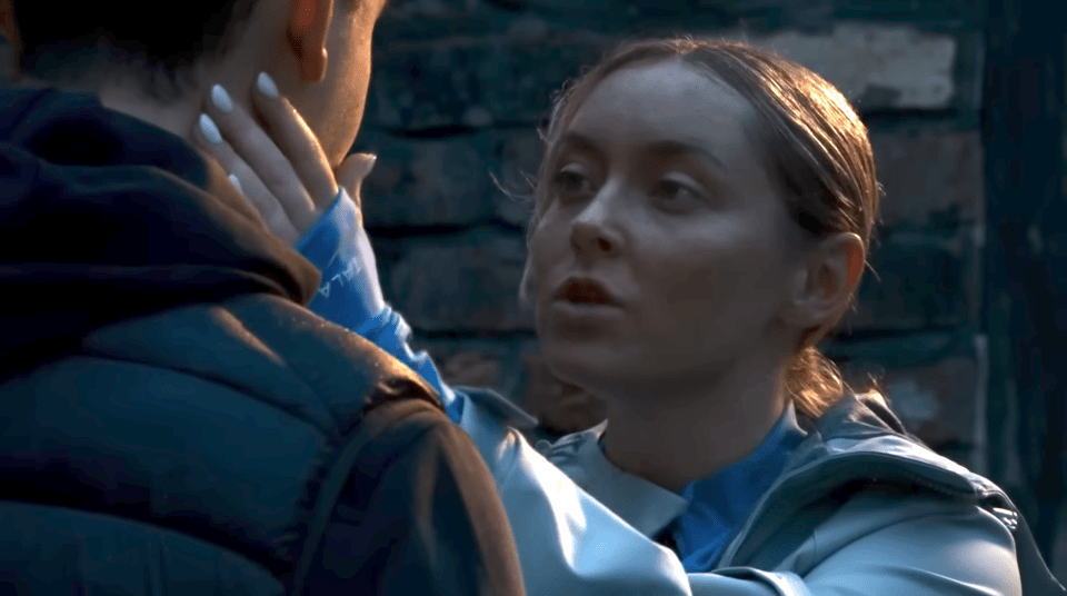 A woman with white nails grabs a man's neck while speaking to him.