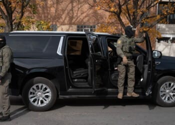 Federal agents stand guard as they are confronted by residents after making a stop while driving in a caravan through the Brighton Park neighborhood on Nov. 6, 2025, in Chicago, Illinois.