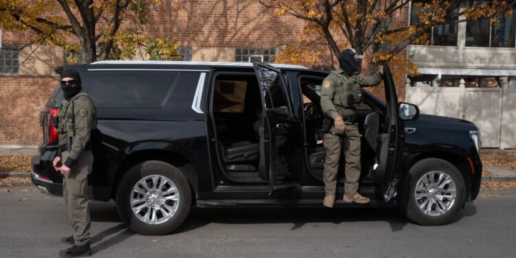 Federal agents stand guard as they are confronted by residents after making a stop while driving in a caravan through the Brighton Park neighborhood on Nov. 6, 2025, in Chicago, Illinois.
