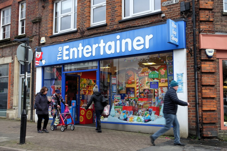 A toy store named "The Entertainer" with several people walking by.