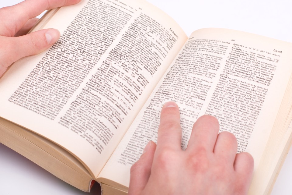 Student's hand pointing to a word in a dictionary.