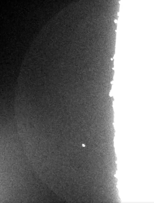 Dark gray surface with a bright white right edge and a single white dot.