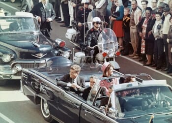 President John F. Kennedy smiles at the crowd that had gathered along the presidential motorcade route in Dallas, Texas, on November 22, 1963