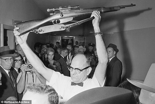 A Dallas policeman holds up the rifle used to kill Kennedy