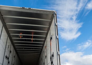 The view of the inside of the rear of a huge empty freight truck with the rear doors open.