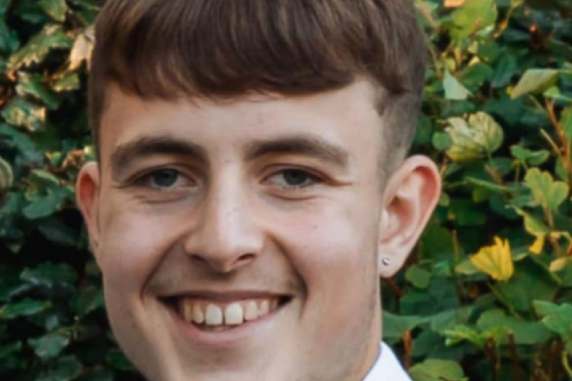 An image collage containing 1 images, Image 1 shows Ethan Powell, a young man smiling and wearing a blue suit with a pink tie and a white boutonnière