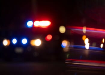 A blurred photograph of police lights flashing on a city street.