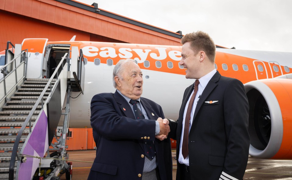 Captain Fred Rivett and Pilot Captain Jamie Smart shaking hands in front of an EasyJet airplane.