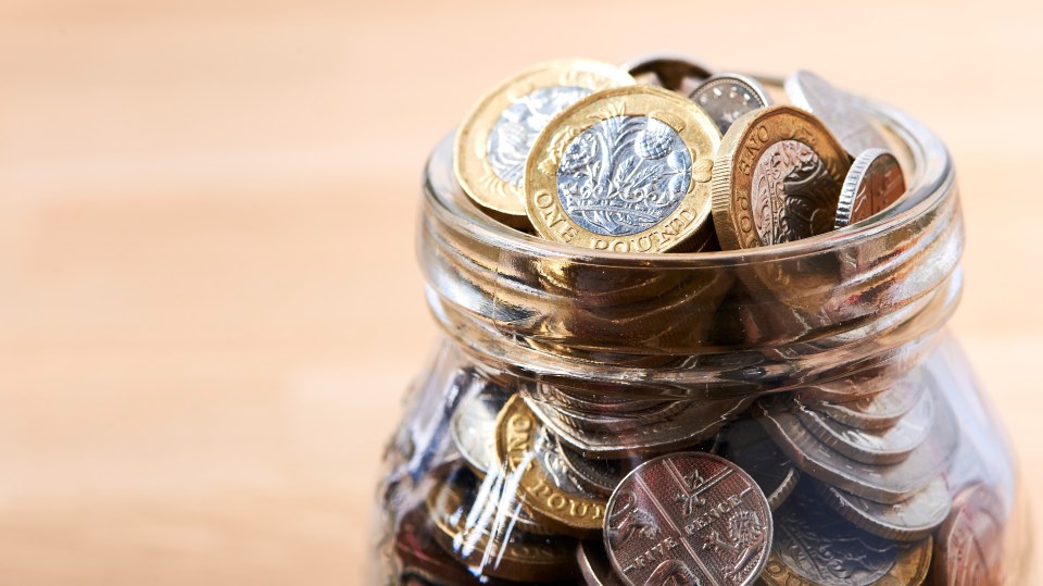 British pound coins in a glass jar.