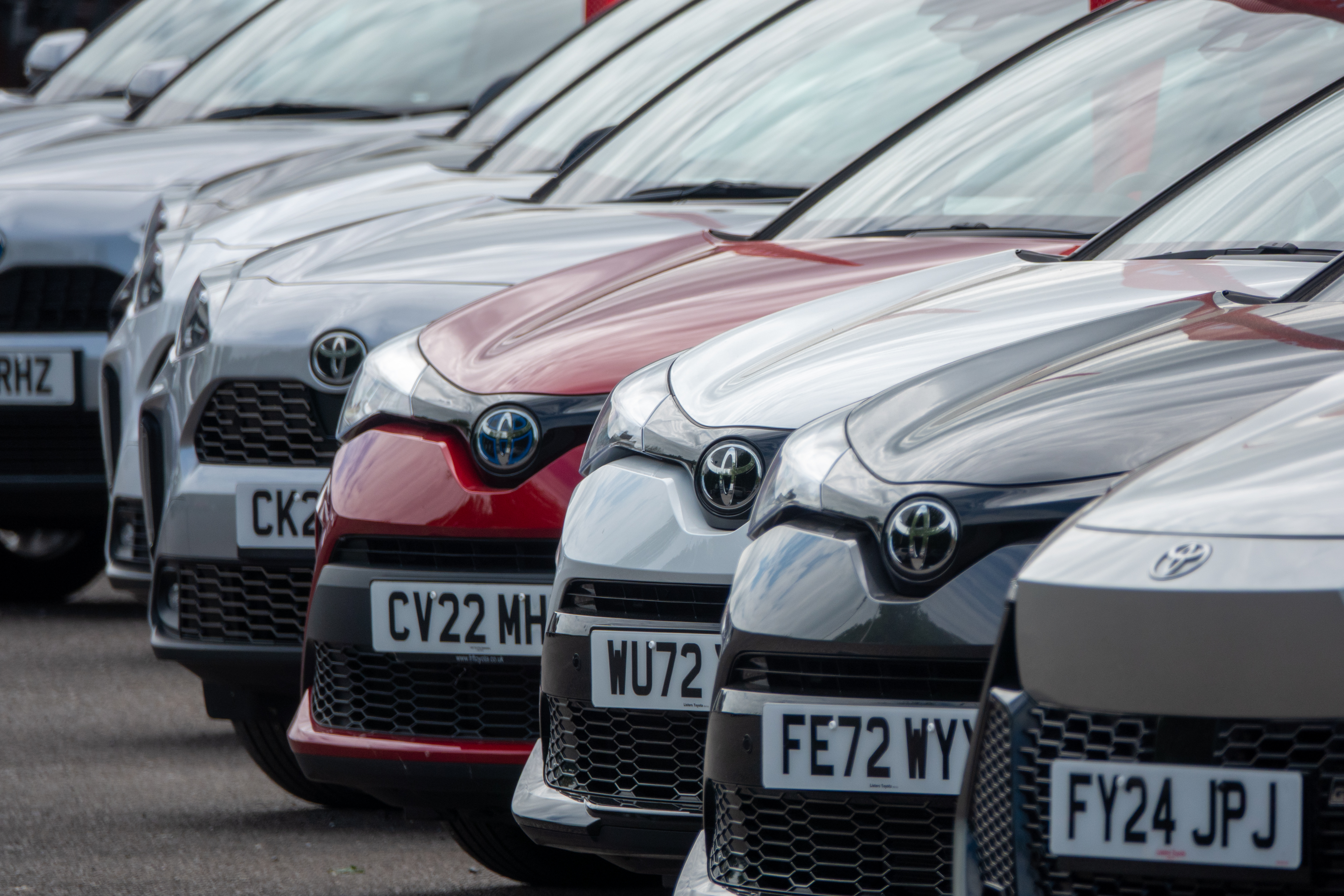 Row of new Toyota cars for sale at a dealership.
