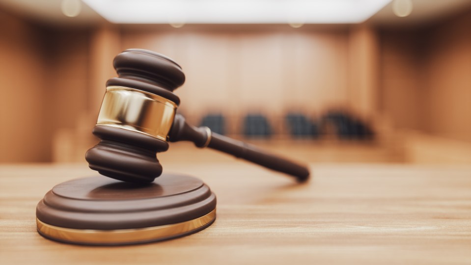 Illustration of a judge's gavel and sounding block on a desk in a courtroom.