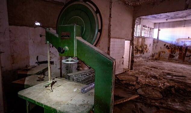A band saw stands beside two bone cutting saws in a room flooded with excrement inside Sednaya Prison, where thousands of people were detained and tortured