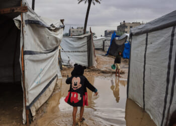 Palestinians walk through a flooded temporary tent camp Tuesday after heavy rainfall in Deir al-Balah, central Gaza Strip.