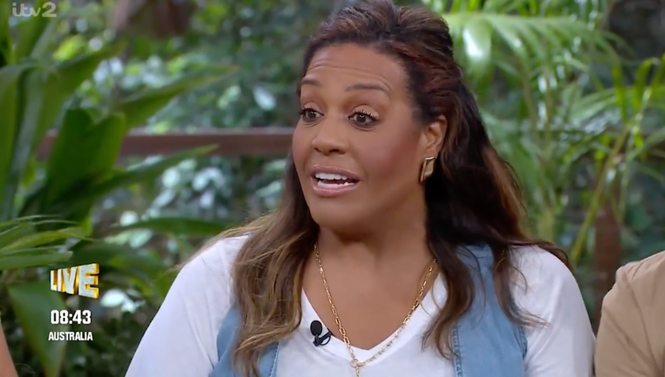 A woman with brown hair and golden earrings is speaking during a live broadcast for ITV2, based in Australia.