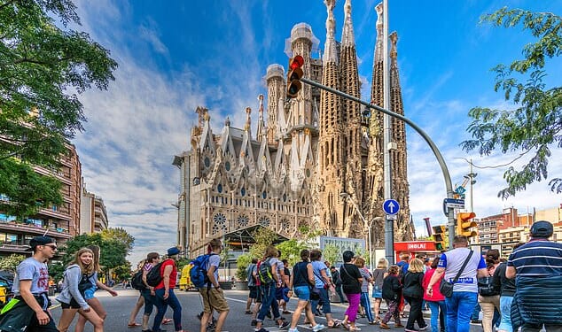 A large group of tourists walks in front of Antoni Gaudi's Sagrada Familia church in Barcelona